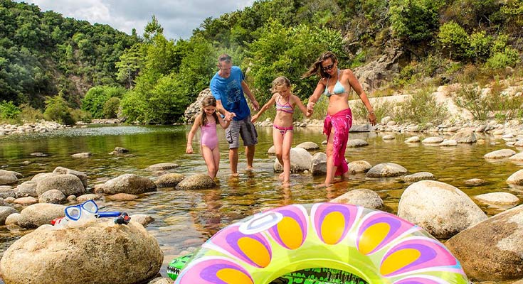 famille profitant du soleil dans la rivière proche du camping